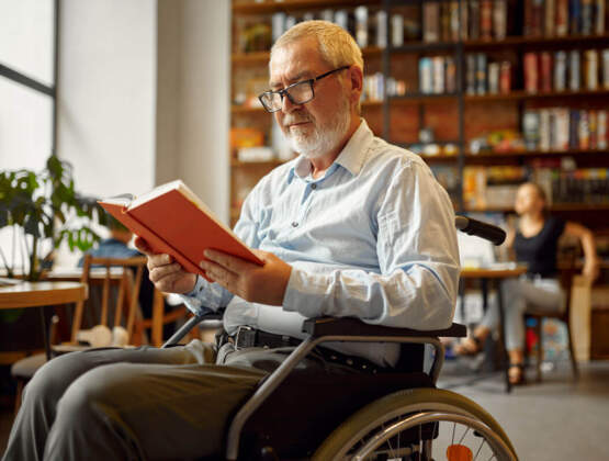 Adult Disabled Man In Wheelchair Reading A Book